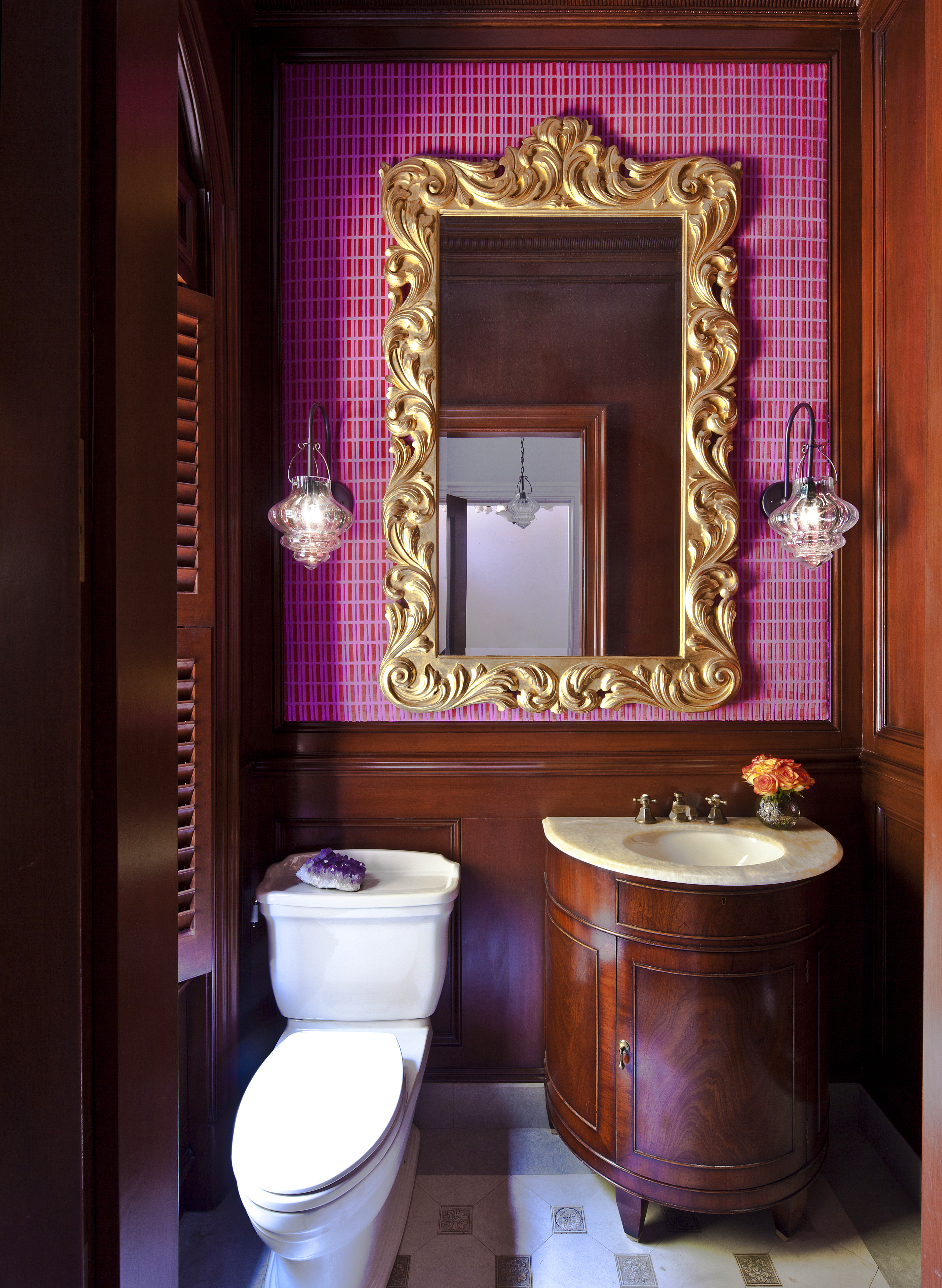 Powder room with traditional wood panelling and gilt mirror, and pink velvet wallpaper, designed by Guillaume Gentet.